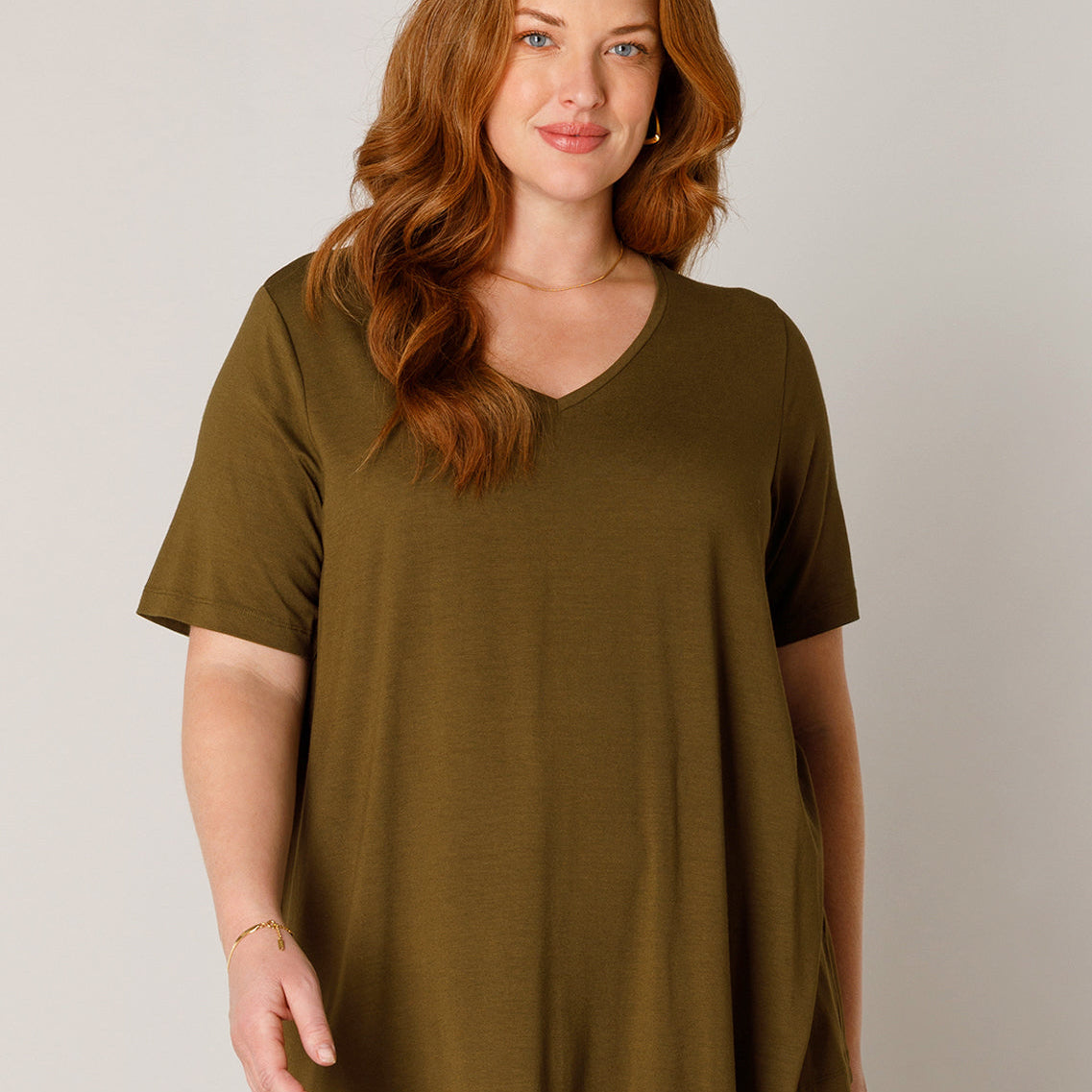 Plus Size Frau mit roten Haaren und rosafarbenem Basic-T-Shirt und hellblauer Jeans