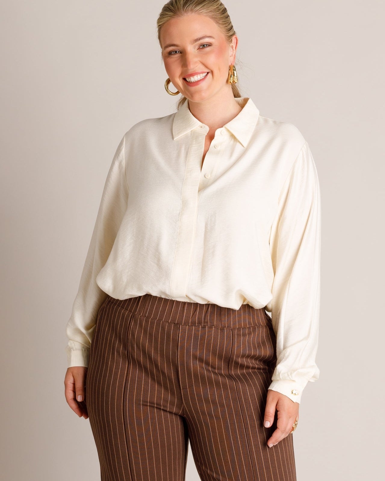 Plus Size Frau mit roten Haaren, hellblauem Blusenhemd und hellblauer Jeans