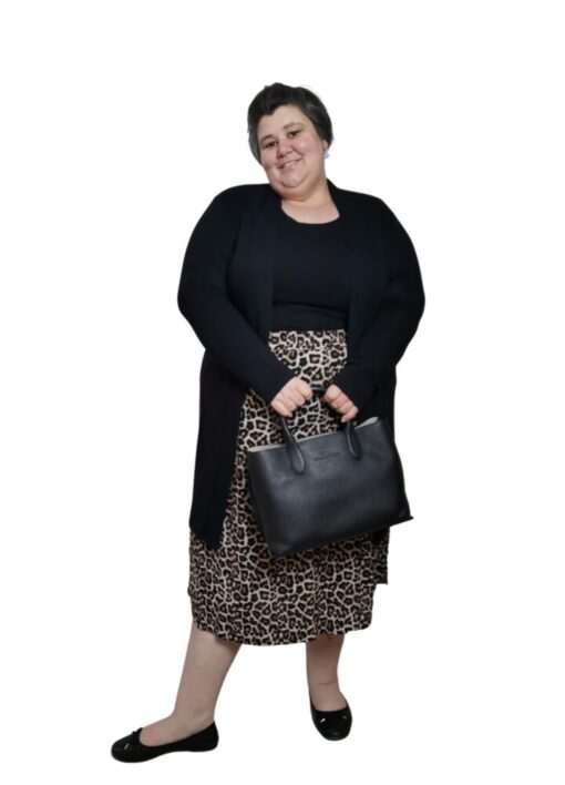 Plus Size Frau mit Rock in Leo-Optik, schwarzes Top und schwarze Jacke, Handtasche in der Hand